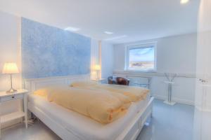 a white bedroom with a bed and a window at Abaluga 1A in Wenningstedt