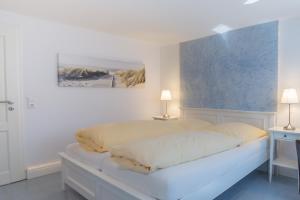 a white bedroom with a bed and two lamps at Abaluga 1A in Wenningstedt