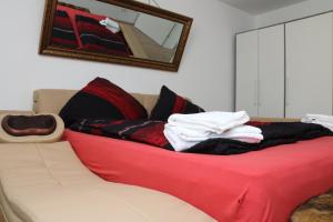 un divano con coperta rossa e cuscini sopra di Aparthotel Kompass A 301 a Essen