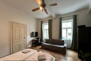 a bedroom with a bed and a couch and a ceiling fan at Discover Danube and Prater Stern from Our 1BR Gem in Vienna