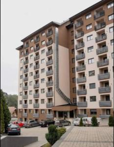 a large building with cars parked in a parking lot at Vila Pekovic Central-Apartman PAMA in Zlatibor