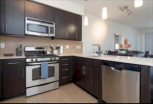 Una cocina con electrodomésticos de acero inoxidable y gabinetes de madera. en Stunning 2BR Penthouse Patio & View Venice MDR, en Los Ángeles