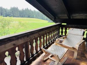 two chairs on a porch with a view of a field at FeWo Staudinger in Irschenberg