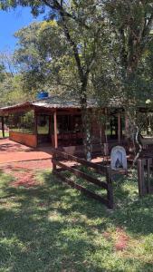 a wooden fence in front of a building with a tree at Sítio das pedras in Ijuí
