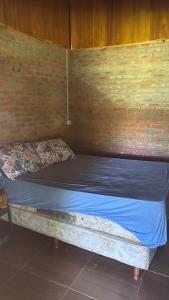 a bed in a room with a brick wall at Sítio das pedras in Ijuí