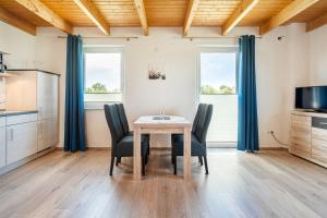 a dining room with a table and chairs and two windows at Ferienwohnung Wattenmeer für 2 Personen am Badesee Tannenhausen in Aurich