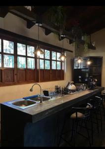 cocina con fregadero y encimera con taburetes en Cabañas Tapalpa la laja, en Los Espinos