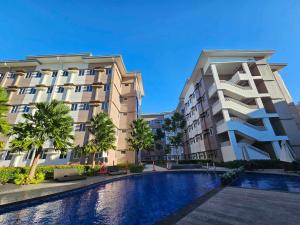 a building with a swimming pool in front of a building at Our Happy Place - Cheer Residences in Marilao