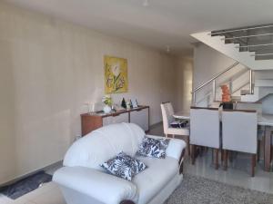 a living room with a white couch and a kitchen at Casa alto padrão a 1 minuto da Praia in Rio das Ostras +16 photos