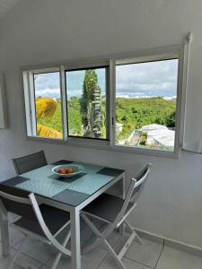 a table and chairs in a room with two windows at Bois patate location in Sainte-Anne