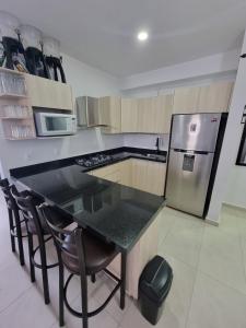 eine Küche mit einem schwarzen Tisch und einem Kühlschrank in der Unterkunft Te Va a Encantar, Torre Turquesa in Mazatlán