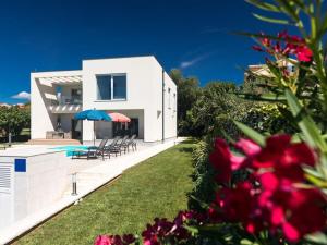 a white house with a swimming pool and a yard at Villa with sea view Comfortable holiday residence in Malinska