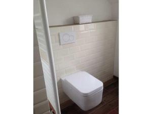 a white toilet in a bathroom with a white tile wall at Pacific Ocean View Comfortable Holiday Residence in Bergen aan Zee