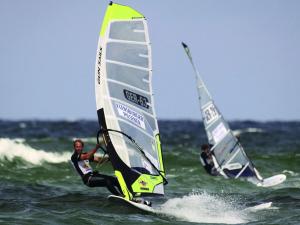 two people windsurfing in the ocean with sailboats at Beach house F994 Comfortable holiday residence in Fehmarn