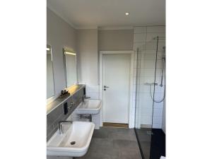Un baño con dos lavabos y una ducha. en Small mountain house Comfortable holiday residence, en Braunlage