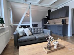 Una sala de estar con un sofá negro y una cocina. en Small mountain house Comfortable holiday residence, en Braunlage