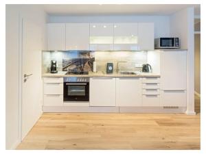 Una cocina blanca con gabinetes blancos y piso de madera. en Beach oasis Comfortable holiday residence, en Norddeich
