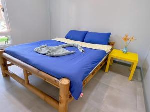 a bed with a blue blanket and a yellow table at Diver Apartment in Panglao
