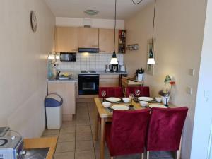 a kitchen with a dining table and red chairs at Möwennest 2 Apartment 35 Comfortable holiday residence in Borkum