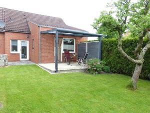 a covered patio with a table and chairs in a yard at At the Leaning Tower Comfortable holiday residence in Suurhusen