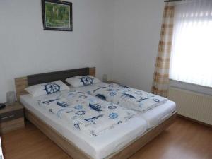 a bed with blue and white sheets and a window at At the Leaning Tower Comfortable holiday residence in Suurhusen