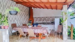 a table with chairs and a kitchen in a patio at Conforto e lazer em Ilheus perto da Praia da Perola in Ilhéus