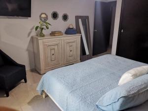 a bedroom with a bed and a chair and a dresser at Departamentos con Alberca in Mazatlán +22 photos