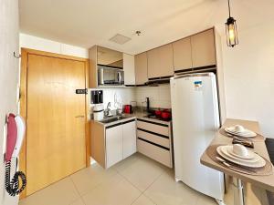 a small kitchen with a refrigerator and a table at Lindo Apartamento dentro do Shopping in Águas Claras