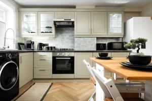 a kitchen with white cabinets and a wooden table at Spacious 3 Bed Home in Glasgow City With Free Parking in Glasgow
