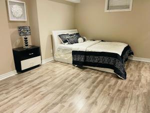 a bedroom with a bed and a wooden floor at Nice and Cozy 2 Bed Bsmt Apt in Pickering