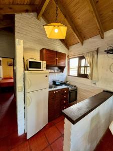 a kitchen with a white refrigerator and a microwave at Cabañas Country in La Paloma