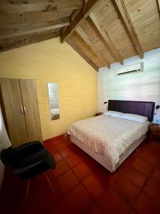 a bedroom with a bed and a black chair at Cabañas Country in La Paloma
