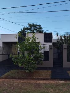 a white house with a tree in front of it at Brisas Iguazú II in Puerto Iguazú