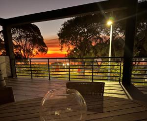 a table with two wine glasses on a deck with a sunset at Seaside Escape Rockingham in Rockingham