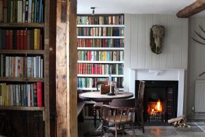 a room with a fireplace and a table and books at Black Lion Hotel in Little Walsingham