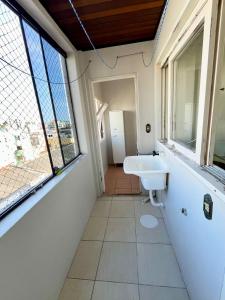 a bathroom with a white sink and windows at Cobertura duplex 3 quartos, centro, terraço e churrasqueira, ideal para família, acesso por escadas in Torres