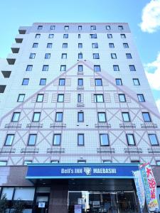 a tall building with a sign in front of it at Bell's Inn Maebashi in Maebashi
