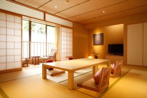 a room with a table and chairs and a television at Yuraku Kinosaki Spa & Gardens in Toyooka