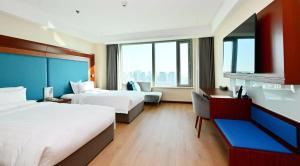 a hotel room with two beds and a couch at Novotel Atlantis Shanghai - Enjoy our great-valued breakfast in our rooftop revolving restaurant with a stunning river view & utilize our FREE self-serviced laundry in Shanghai