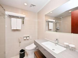 a white bathroom with a sink and a toilet at Novotel Atlantis Shanghai - Enjoy our great-valued breakfast in our rooftop revolving restaurant with a stunning river view & utilize our FREE self-serviced laundry in Shanghai
