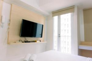 a bedroom with a flat screen tv on a wall at New and Nice Designed Studio at Tokyo Riverside PIK 2 Apartment By Travelio in Rawalembang