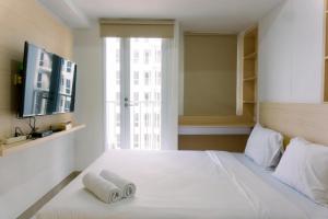 a bedroom with a large white bed with towels on it at New and Nice Designed Studio at Tokyo Riverside PIK 2 Apartment By Travelio in Rawalembang