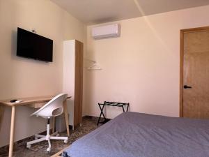 a bedroom with a bed and a desk and a television at Casa Cañonero, a magic place, 4 room in Oaxaca City
