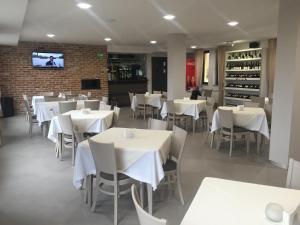 a restaurant with white tables and chairs and a tv at La Casa Hotel in Tsigov Chark