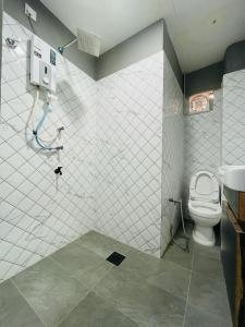 a tiled bathroom with a toilet and a shower at Hotel Casaria in Paka