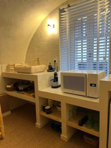 une cuisine avec un four micro-ondes sur un comptoir et une fenêtre dans l'établissement 60 m2 Dar blue Centre Historique Clermont-Ferrand Cathédrale, à Clermont-Ferrand