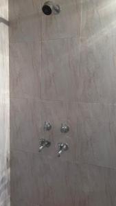 a shower with two silver faucets in a bathroom at Vrinda stays in Chhatikara