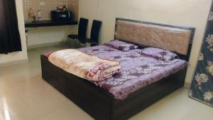 a bedroom with a bed with a wooden headboard at Vrinda stays in Chhatikara
