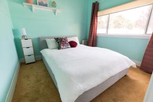 Un dormitorio con una cama blanca con una ventana. en Cosy, historic & affordable 2-bed apartment - 5kms from Castlemaine, 2kms from Calder, en Barkers Creek