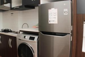 a kitchen with a stainless steel refrigerator and a dishwasher at Homey and Minimalist 2BR at Patraland Urbano Apartment By Travelio in Bekasi